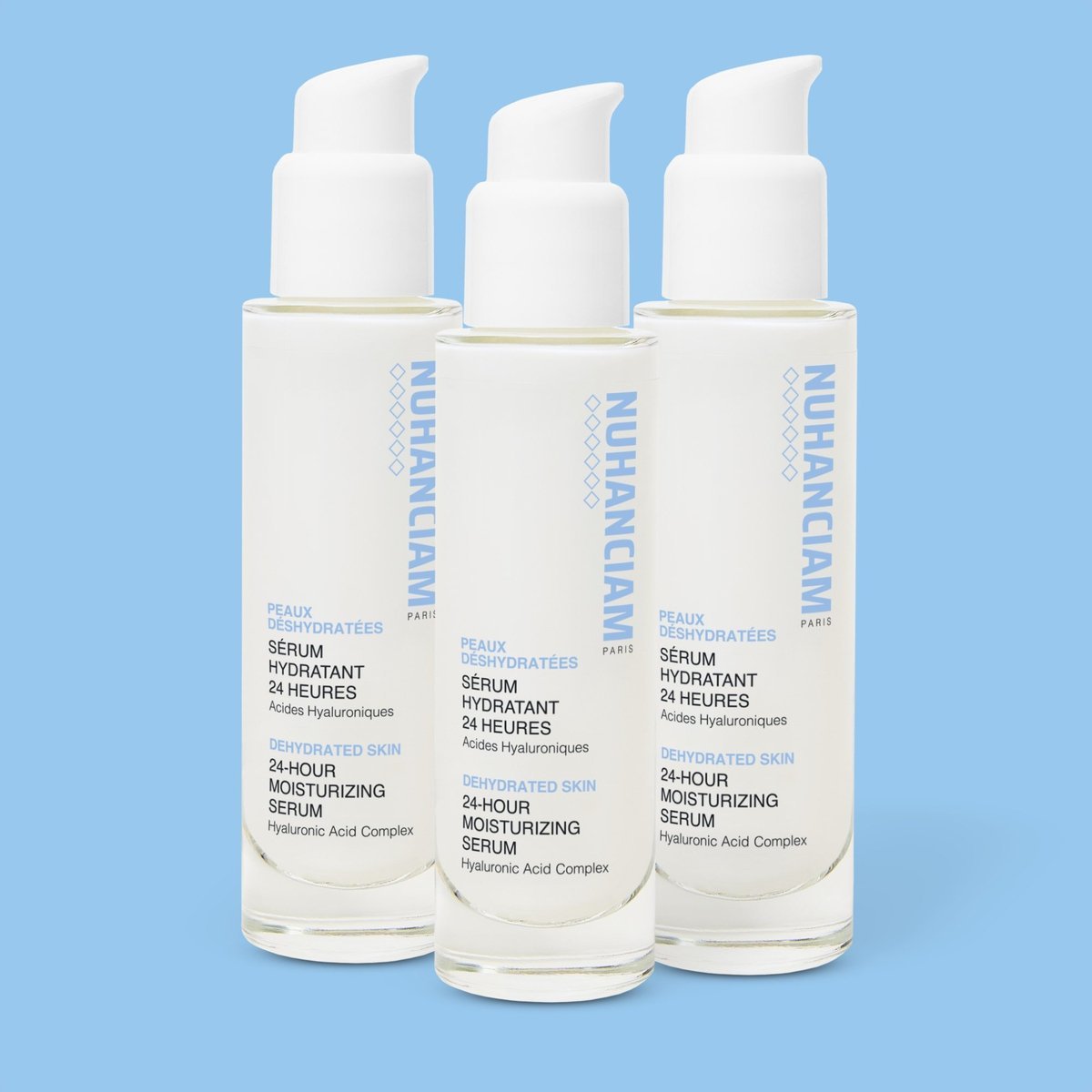 Trois flacons de Sérum Hydratant 24h NUHANCIAM aux 4 Acides Hyaluroniques sur fond bleu